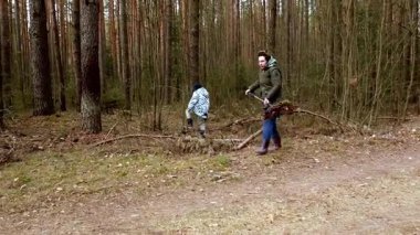 İki çocuk yemyeşil bir ormanı keşfederken, etraflarında ağaçlar ve yeşilliklerle çevrili sakin bir günün tadını çıkarırken, çubuklar toplayıp çevreleriyle etkileşime geçiyorlar..