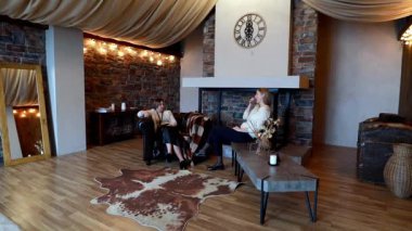 İki arkadaş, sıcak melodiler ve kırsal dekorlarla çevrili şık bir salonda rahatça oturuyorlar. Sakin bir atmosferde sohbet edip eğleniyorlar..