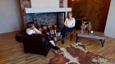 İki arkadaş sıcak bir oturma odasında derin bir sohbetin tadını çıkarıyorlar. Sıcak ışıklandırma ve şık dekorasyon büyüleyici diyalogları için rahatlatıcı bir atmosfer yaratıyor..