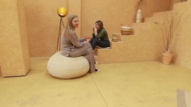 Samimi ve minimalist bir ortamda, iki arkadaş rahatça otururken kahkahalar ve hikayeler paylaşır. Sakinleştirici atmosfer bağlantılarını ve konuşmalarını güçlendirir..