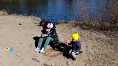 Bir aile nehir kenarında vakit geçirirken rahatlatıcı bir gün başlıyor. Çocuklar kumda oynarken yetişkinler sıcak havanın ve doğal çevrenin tadını çıkarıyorlar..