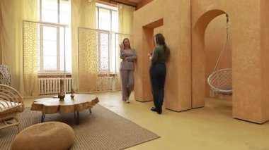 İki kadın, şık ve davetkar bir odada sıcacık renkler ve modern mobilyalar, asılı bir sandalye ve dokuma duvarlar da dahil olmak üzere sağlıkla ilgili bir sohbete girişiyor..