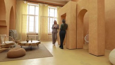 İki kadın, sıcak tonlarla ve eşsiz mimari özelliklerle dolu modern ve minimalist bir alanda iç mimari tasarım hakkında sohbet ediyorlar. Oda doğal ışıktan iyi aydınlatılmış..