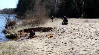 Çocuklar kumlu gölleri keşfeder, suda oynar ve kumdan kaleler inşa eder, bir yetişkin ise yakınlarda bir köpekle dinlenir. Neşeli, neşeli bir gün neşe ve kahkaha dolu.
