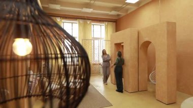 Modern bir yaratıcı stüdyoda, iki kadın tasarım kavramları hakkında sohbet eder. Sıcak iç mekan eşsiz yapısal elementler ve yumuşak ışıklandırma ile vurgulanarak atmosferi güçlendirir..