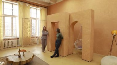 İki kadın, minimalist dekor ve eşsiz mimari unsurlarla donatılmış geniş, güneşli bir odada iç tasarım fikirlerini tartışıyor. Sıcak melodiler davetkar atmosferi güçlendirir..