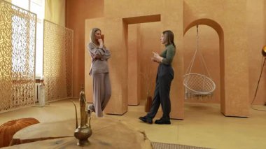 Kadınlar rahat bir mekanda rahat rahat sohbet ediyorlar. Sıcak, tarafsız tonlarda ve şık dekorasyonlarda. Atmosfer gevşemeyi ve bağlanmayı teşvik eder..