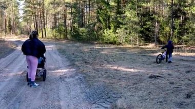 Bir aile öğleden sonra bir ormanın huzurunu keşfeder. Bir kadın bebek arabasıyla yürürken, bir çocuk ağaçlar ve güneşli yapraklarla çevrili kirli bir yolda bisiklet sürerken görülüyor..