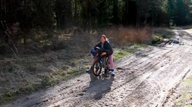 Orman bölgesinde toprak bir patika boyunca dağ bisikleti sürmekten keyif alan bir insan. Güneş ışığı ağaçların arasından süzülür, yere gölge düşürür..