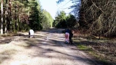 Güneşli bir günde iki kişi ağaçlık yolda köpekleriyle yürür. Boş zamanlarında doğal ortamın ve temiz havanın tadını çıkarırlar..