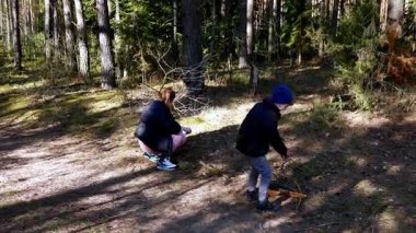 Ebeveynleri sakin bir ormanda onlara göz kulak olurken iki küçük çocuk dışarıda oynaşıyor. Güneş ağaçların arasından süzülerek keşif için sıcak bir atmosfer yaratır..