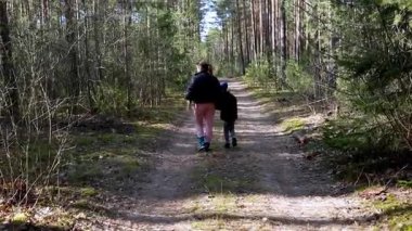 Aileler uzun ağaçlar ve yemyeşil ağaçlarla çevrili bir orman yolunda huzurlu bir yürüyüşün tadını çıkarıyorlar. Sahne, doğadaki neşe ve bağlantı anlarını yakalar..