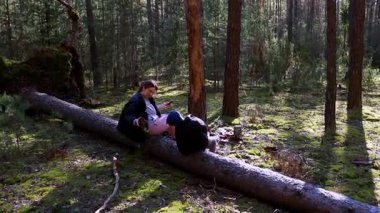 İki insan gür bir ormanda uzun ağaçlar ve yeşilliklerle çevrili bir kütüğün üzerinde dinlenerek huzurlu bir anın tadını çıkarırlar. Güneş ışığı içinden süzülüp barışçıl bir atmosfer yaratıyor..