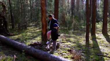 Bir kadın ve genç bir çocuk, uzun ağaçlar ve yumuşak yosunlarla dolu yemyeşil bir ormanda huzurlu bir günün tadını çıkarıyorlar. Güneş ışığı dalların arasından süzülüp rahatlatıcı bir atmosfer yaratır..