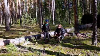 Çocuklar ormanda uzun ağaçların ve yemyeşil çimlerin arasına ağaç dikerek maceranın tadını çıkarıyorlar. Bu etkinlik çevresel farkındalığı ve takım çalışmasını teşvik etmektedir..