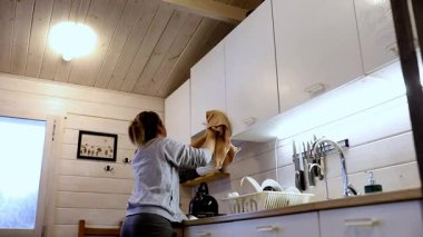 Bir kadın, ahşap bir kulübede mutfak dolaplarını düzenler ve temizler. Üretken bir öğleden sonranın tadını çıkarırken dikkatlice yüzeyleri siler ve eşyaları kaldırır..