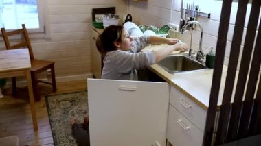 İyi tasarlanmış bir mutfakta, bir kadın hafta sonu yemeklerini hazırlarken bulaşıkları ve çatal bıçakları dikkatlice düzenler..