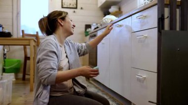 Bir kadın mutfak dolaplarını düzenler ve düzenler, ev ortamında etkili depolama yöntemleri sergiler. Kolay erişim ve temizlik için eşyalar düzenliyor..