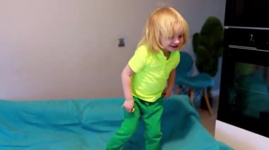 Neşeli bir çocuk neşe ve neşe dolu bir yaşam alanında renkli bir battaniyeyle meşgul olur. Gün ortası ışığı yuvayı dolduruyor, anı ısıtıyor..