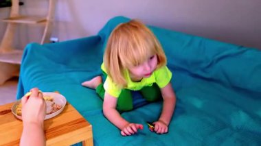 Parlak yeşil elbiseli bir çocuk yemek yerken merakını ve neşesini göstererek kanepeyi keşfediyor. Ortam sıcak ve aile dostu, rahatlamak için mükemmel..