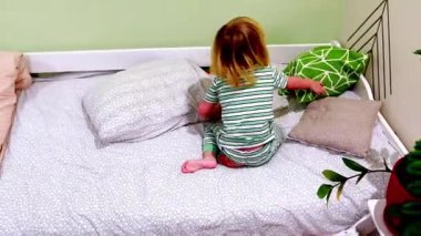 Çizgili pijama giymiş neşeli bir çocuk yatağındaki renkli yastıkları keşfediyor. Kahkahalar odayı dolduruyor, küçük olan rahat ortamlarda eğlenceli anların tadını çıkarırken..