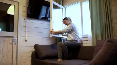 Konforlu bir kamarada bir kadın kanepeye oturur ve pencereyi mutlu bir şekilde açar. Temiz havanın ve uzaya akan doğal ışığın tadını çıkarıyor. Sıcak atmosferi arttırıyor..