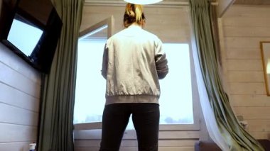 Güneş ışığı büyük pencerelerden içeri girerek sıcak bir atmosfer yaratırken, bir kişi kabin alanını düzenler, nesneleri ve yüzeyleri temizler..