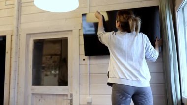 Parlak, davetkar bir yaşam alanında tahta bir duvara monte edilmiş düz ekran bir televizyonu siliyor. Doğal ışık odanın temiz atmosferini arttırır..