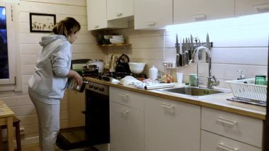 Bir insan sıcak ışıklandırmayla dolu modern bir mutfakta yemek hazırlıyor. Mutfak iyi donanımlı, çeşitli mutfak aletleri ve yemek malzemeleri sergileniyor..