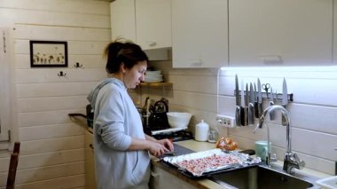 Parlak, davetkar bir mutfakta sebze doğrayan bir kadın, çeşitli mutfak aletleri ve malzemeleriyle çevrili olarak yemek yapma görevlerine odaklanıyor..