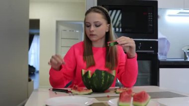 Bir insan modern bir mutfakta eşsiz bir karpuz aperatifi hazırlıyor. Meyveyi zarif bir şekilde dilimleme ve yeme metodunu sergiliyor..
