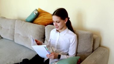 Genç bir kız kanepede rahatça oturur, kitap okumaya dalmıştır. Oda doğal ışıkla dolu, sıcak ve davetkar bir atmosfer yaratıyor..