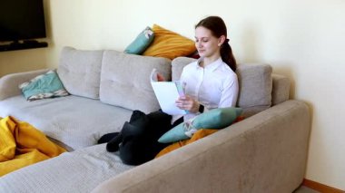 Genç bir kadın, parlak bir oturma odasındaki bir kanepede rahatça oturur, bir kitaba dalmıştır. Etrafını minderler sarmış ve sarı bir battaniye yakınlarda uzanıyor. Rahatlamış bir atmosfer yaratıyor..