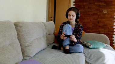 Genç bir insan, sıcak bir oturma odasındaki rahat bir kanepede tek başına oyun oynamaktan zevk alır. Yumuşak ışıklandırma ve gevşek bir atmosfer oyun oynamaya odaklandıklarında deneyimi güçlendirir.