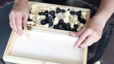 Bir kadın öğleden sonra terasta oturur ve satranç oynar. Tahtayı ve parçaları bir maç için hazırlıyor..