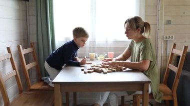 Bir anne ve oğlu yemek masasında Jenga oynuyorlar. İkisi de oyundan zevk alıyor ve birlikte eğleniyorlar..