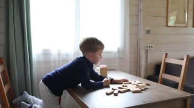 Genç bir çocuk kendi evinde annesiyle Jenga oynuyor. Diz çöküyor ve kuleden çıkmak için bir bloğa uzanıyor. Kule bir masanın üzerinde ve şimdiden birkaç blok var.