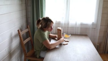 Kafkasyalı bir anne evinde oğluyla Jenga oynuyor. Dikkatlice bir kuleden tahta blokları kaldırıyor, çökmemesi için çabalıyor. Video onun konsantrasyonunu ve...