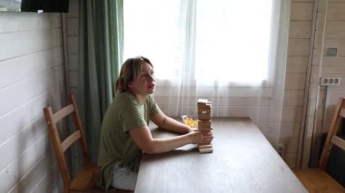 Bir anne ve küçük oğlu evlerinde klasik masa oyunu Jenga oynuyorlar. Kuleyi çökertmeden blokları sökmeye çalışırken gülüp eğleniyorlar. Video neşeyi yakalıyor.