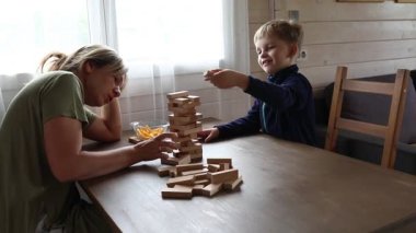 Bir anne ve oğlu evde Jenga oyunu oynuyorlar. İkisi de parlak bir odadaki ahşap bir masada oturuyorlar. Anne dikkatle Jenga kulesinden bir blok çekiyor, oğlu ise...