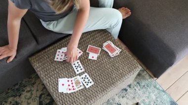 Bu video bir kadının oturma odasındaki masada kağıt oynadığını gösteriyor. O bir kanepede oturuyor ve iskambil oyununa hazırlanıyor gibi görünüyor. Video genel bakış açısından çekiliyor ve kadınların ellerine ve elindeki kartlara odaklanıyor.