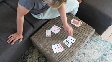 Bu video bir kadının oturma odasındaki masada kağıt oynadığını gösteriyor. Kanepede oturuyor ve kamera dışında biriyle oyun oynuyor gibi görünüyor. Video, o kartları dikkatlice masaya sererken anı yakalıyor..