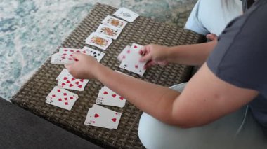 Bir kadın bir deste iskambil kağıdını masaya seriyor. Kartlar sırayla dağıtıldı, ve o dikkatlice onları birer birer yerleştiriyor. Video gündüz kaydedildi, doğal ışıklandırmayla kanıtlandığı gibi..