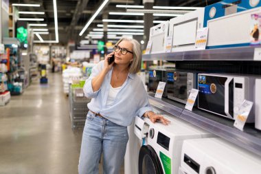 Bir kadın, modern bir mağazada alışveriş yaparken ev aletleriyle meşgul oluyor ve günlük hayatı ve alışveriş yolculuğunu gösteriyor. İfadeleri, perakendecilikteki karar verme mekanizmasını yansıtıyor..