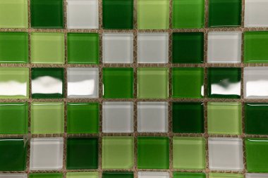 Değişik yeşil ve şeffaf tonlarda cam fayansların canlı bir düzenlenmesi dekoratif bir mozaik oluşturur. Fayanslar düzgün hizalanmış, görsel cazibelerini arttırıyor..