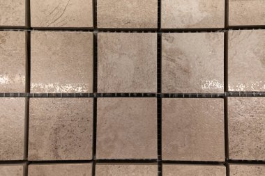 Değişen bej ve gri tonlarına ve farklı dokularına sahip kare karolardan oluşan bir ızgaranın yakın görüntüsü. Bu düzenleme, ev dekorasyonu ve yenileme projeleri için ideal benzersiz desenleri vurgular.