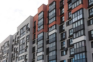 Bu görünüm, çağdaş mimari tarzını ve kentsel yaşam eğilimlerini vurgulayarak hareketli bir yerleşim alanına yerleştirilmiş yüksek katlı apartmanlar dizisini gösterir..