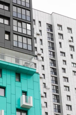 Görüntüde çağdaş bir yerleşim bölgesindeki yüksek katlı apartmanlar yer alıyor. Farklı mimari tasarımları, kiralık ve ipotek seçeneklerini vurgulayarak kentsel yaşam seçeneklerini vurguluyor.