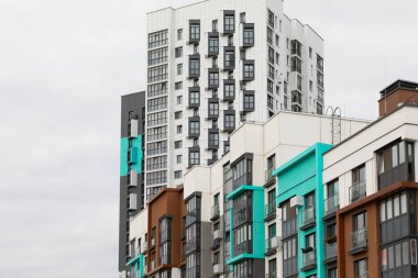 İmaj, modern mimari ve kentsel yaşamı vurgulayarak, canlı ve sessiz renklerin bir karışımının yer aldığı bir yerleşim yerindeki yüksek apartman binalarını gösteriyor..