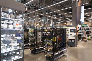 İyi organize edilmiş bir hırdavat mağazası, tamir ve ev geliştirme için gerekli aletler, malzemeler ve malzemelerle dolu koridorlara sahiptir. Müşteriler ihtiyaçları için raflara bakarlar..